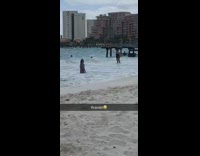 Girl poses in water at beach friend take picture waves come