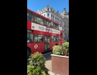 Three people tiktok dance beside double-decker bus
