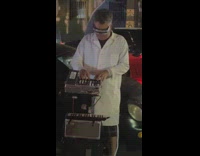 Guy wearing white coat plays music on sidewalk 