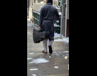 Man wear slides carry guitar case street snow