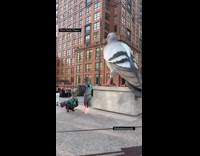Couple dressed as pigeon poses at sculpture