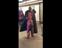 Man in sequin pants and sparkly red vest dances and sings in subway station