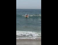 Guy orange surfboard rides wave into guy on green surfboard