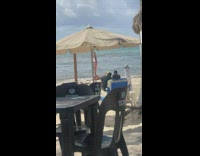 Woman poses at the beach helped by two beach staff