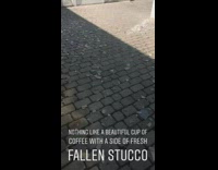 Gray piece of brick wall falls off side of tall building and breaks on the ground near cafe patio