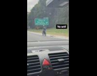 Guy rides electric bike on freeway 