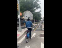 Cyclist blue jacket carry basketball hoop on head