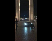Guy sits on ground by white sports car 