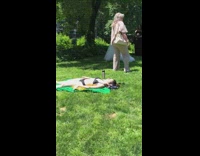 Woman tanning at park while couple take marriage photos next to her