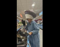 Lady in hat laughs holding frying pan 