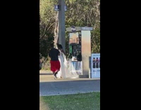 Woman wedding dress spread veil gasoline station