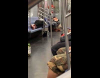 Clown in black and white sits in corner of train 