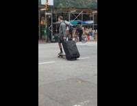 Guy rides electric skateboard with luggage suitcase 