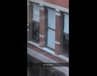 man on window ledge cleaning building window