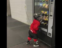Little boy wearing hockey uniform hits vending machine 