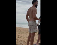 Man takes a photo of a bag and a hat at the beach