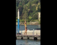 Woman bikini boots stand on bridge beside boat