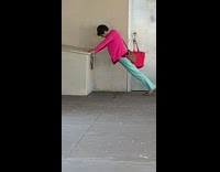 Woman leans on electric box and does hip thrusts at subway station