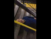 Man blue sweater sleeps on subway station stairs