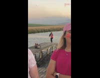 Pink shirt girl jumps wood dock sunset
