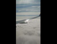 Airplane flies over white clouds wing window 