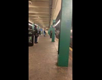 Shirtless sweaty man punches green pillars with boxing gloves in subway station