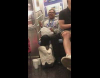 Man in NYU jacket pours beer into cups on the floor in subway train