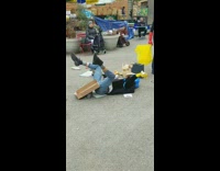 Person lays on the floor in the middle of a swap meet and flails their arm and legs in the air