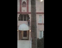 Man brown jacket hang balcony video shoot