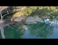 Black shorts guy jumps off rock water 