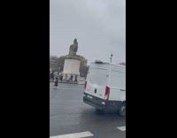 Woman in black dress poses in the middle of the street while it rains