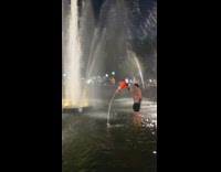 Man in fountain dressed as cop with orange cone