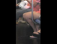 Woman pink shorts sits down on subway train knees look like a face 