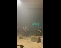 Men light up fireworks inside of empty room with 2019 neon sign