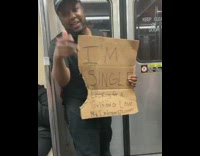Guy holding sign on subway that he is looking for love