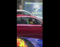 Guy shakes yellow maracas while driving car 
