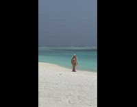 Lady in Bikini Coat and Boots Walks on Beach