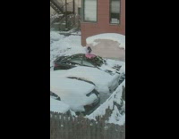 Woman uses broom to wipe of snow from car 