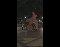 Two people pushing trojan horse rabbit through park at night