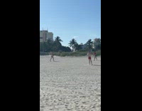 Two guys red shirt catch football beach