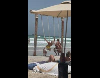 Woman takes selfie video while on beach swing