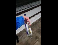 Guy walk outside night holding alcohol bottle