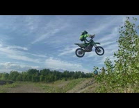 Guy jumps hill on green dirt bike 