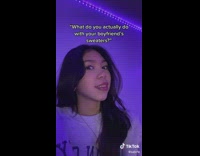 Girl in grey sweater in purple blue light room looks over at camera