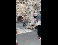 White shirt guy sits stone wall arch 