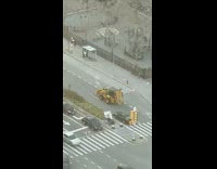 Yellow bulldozer drives down street 