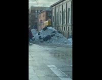 Black trash bags on large snow pile 