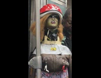 Mannequin dressed in purple underwear, red helmet, brown leather jacket, high heel zippers on subway train