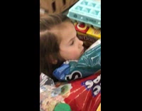 Little girl sits in full shopping cart 