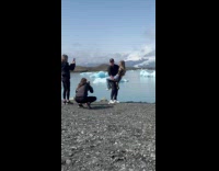 Man carries woman with bottle icy shore